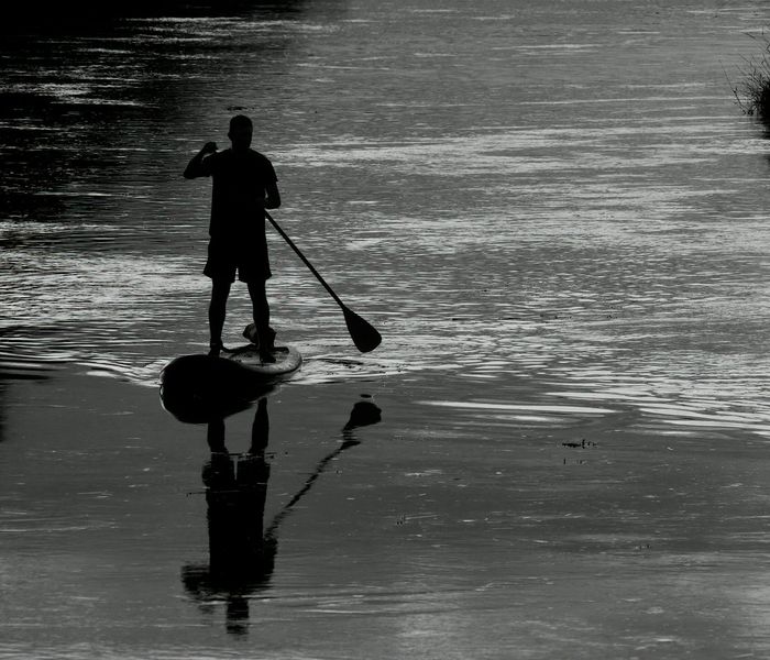 Person stretching outdoors during sunrise with a calm expression.